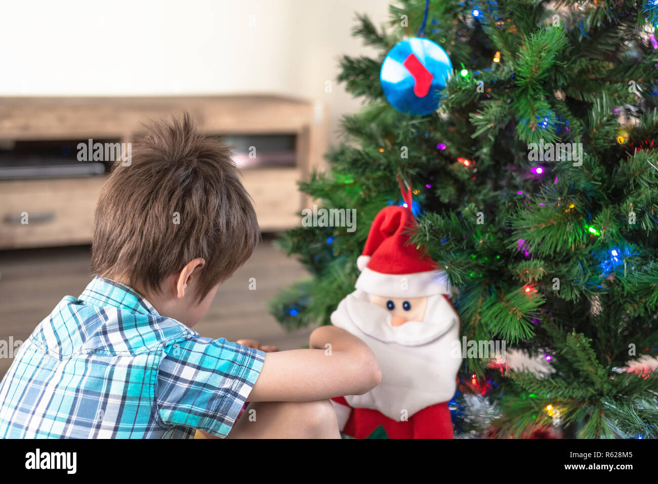 Child making a wish at Santa Claus near Christmas tree Stock Photo
