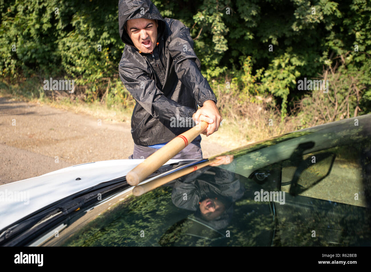 Attacker trying to break a windshield with a baseball bat Stock Photo