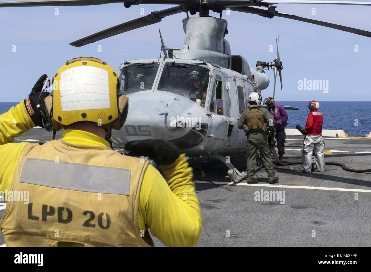 CORAL SEA (Nov. 19, 2018) Aviation Boatswain’s Mate (Handling) 3rd Class Walter Rutherford, from Cheyenne, Wyo., signals a UH-1Y Huey helicopter, assigned to Marine Light Attack Helicopter Squadron (HMLA) 469, as it takes fuel on the flight deck of the amphibious transport dock ship USS Green Bay (LPD 20) prior to cross deck flight operations with the Royal Australian Navy helicopter landing dock ship HMAS Adelaide (L01). Green Bay, part of Commander Amphibious Squadron 11, is operating in the region to enhance interoperability with partners and serve as a ready-response force for any type of  Stock Photo