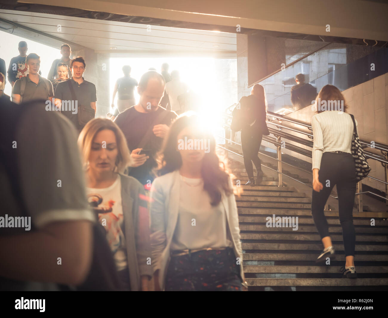 Moscow, Russia - September 6, 2018: Ordinary people go up and go down to the underground subway at rush hour. People go down to the underpass. Silhouettes of people walking down the steps against the backdrop of the sun. Stock Photo