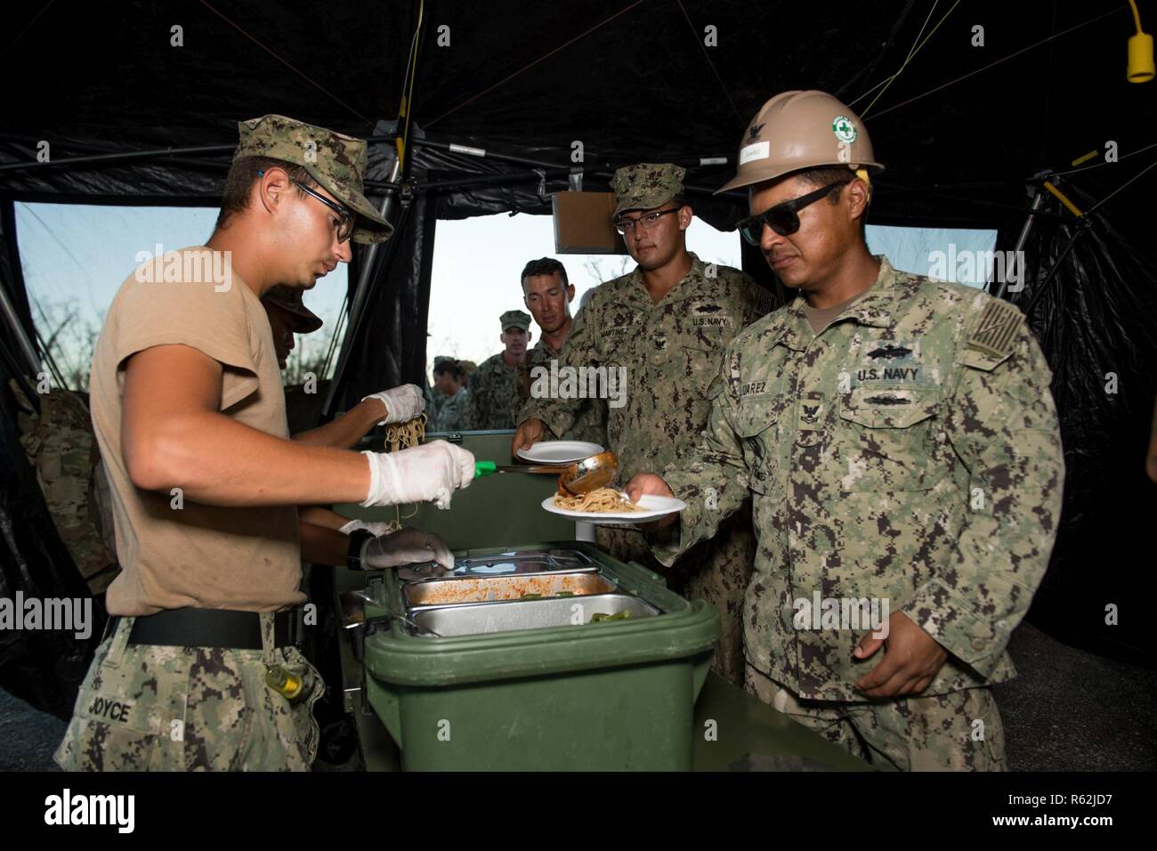 TINIAN, Commonwealth of the Northern Mariana Islands (Nov. 18, 2018) Construction Mechanic Construction Apprentice James Joyce, assigned to Naval Mobile Construction Battalion 1, Detachment Guam, from Pittsburgh, serves dinner to Sailors during recovery efforts. Service members from Joint Region Marianas and U.S. Indo-Pacific Command are providing Department of Defense support to the Commonwealth of the Northern Mariana Islands' civil and local officials as part of the Federal Emergency Management Agency-supported Super Typhoon Yutu recovery efforts. Stock Photo