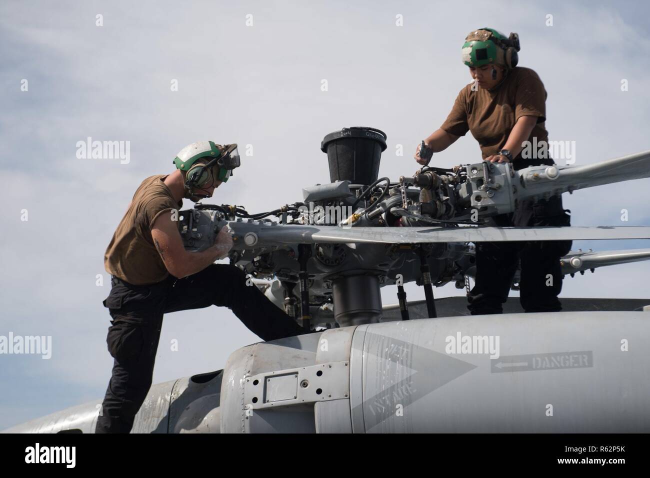 PACIFIC OCEAN (Nov. 20, 2018) Aviation Electronics Technician 3rd Class Alton Laussade, left, from Raceland, Louisiana, and Aviation Machinist’s Mate Airman Remely Culas, from Garden Grove, California, clean the main rotor pylon of an MH-60R Sea Hawk, with Helicopter Maritime Strike Squadron (HSM) 37, aboard the Arleigh Burke-class guided-missile destroyer USS Chung-Hoon (DDG 93). Chung-Hoon is underway conducting routine operations as part of Carrier Strike Group (CSG) 3 in the U.S. Pacific Fleet area of operations. Stock Photo