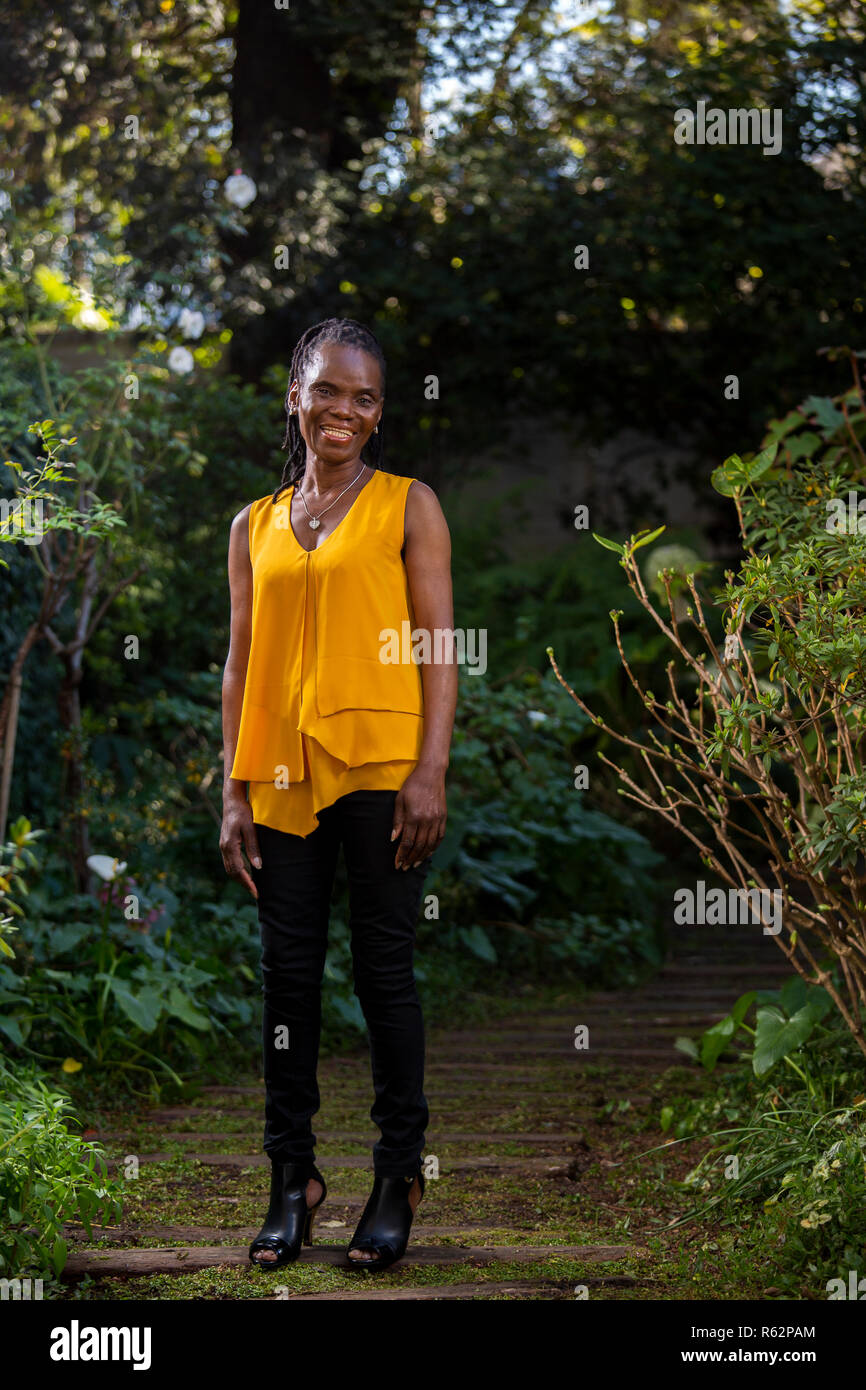 Elderly African woman standing on a garden path Stock Photo