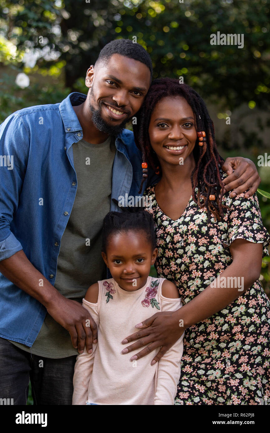 A mother, father and daughter holding each other affectionately in a garden Stock Photo