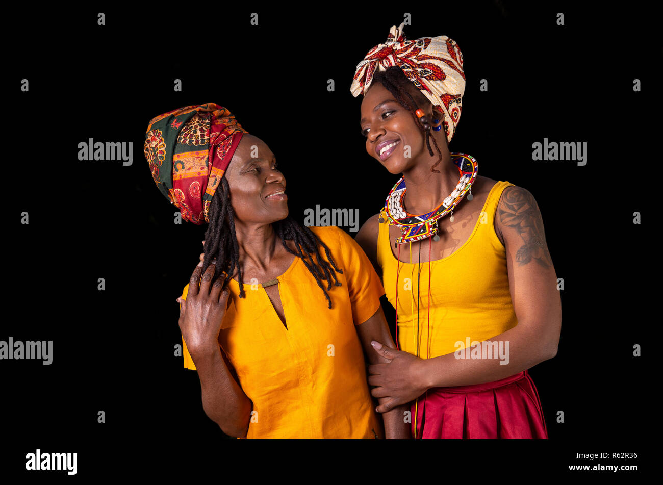 An African mother and daughter standing close together against a black background Stock Photo