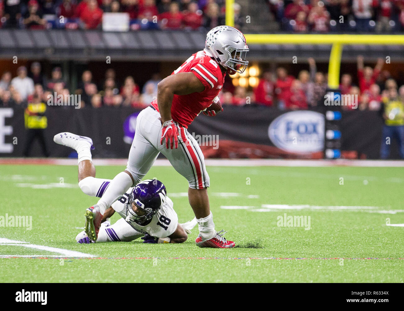 Indianapolis, Indiana, USA. 01st Dec, 2018. Ohio State running back J.K. Dobbins (2) runs with the ball as Northwestern defensive back Cameron Ruiz (18) pursues during NCAA Football game action between the Northwestern Wildcats and the Ohio State Buckeyes at Lucas Oil Stadium in Indianapolis, Indiana. Ohio State defeated Northwestern 45-24. John Mersits/CSM/Alamy Live News Stock Photo