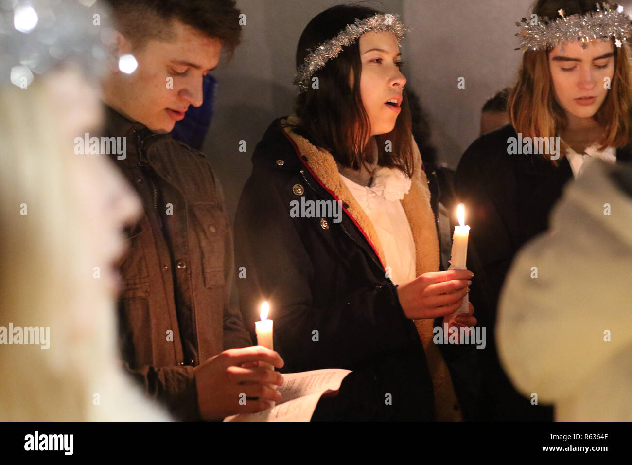 Gdansk, Poland 3rd. December 2018 Young girls from Kalmar, Sweden dressed in a white dress and a red sash (as the symbol of martyrdom) carrying candles singing in the Gdansk Old City centre. Swedish girls dressed as Saint Lucy (Sankta Lucia)  carry cookies in procession and sing a songs. It is said that to vividly celebrate St. Lucy's Day will help one live the long winter days with enough light  Credit: Max Ardulf/Alamy Live News Stock Photo