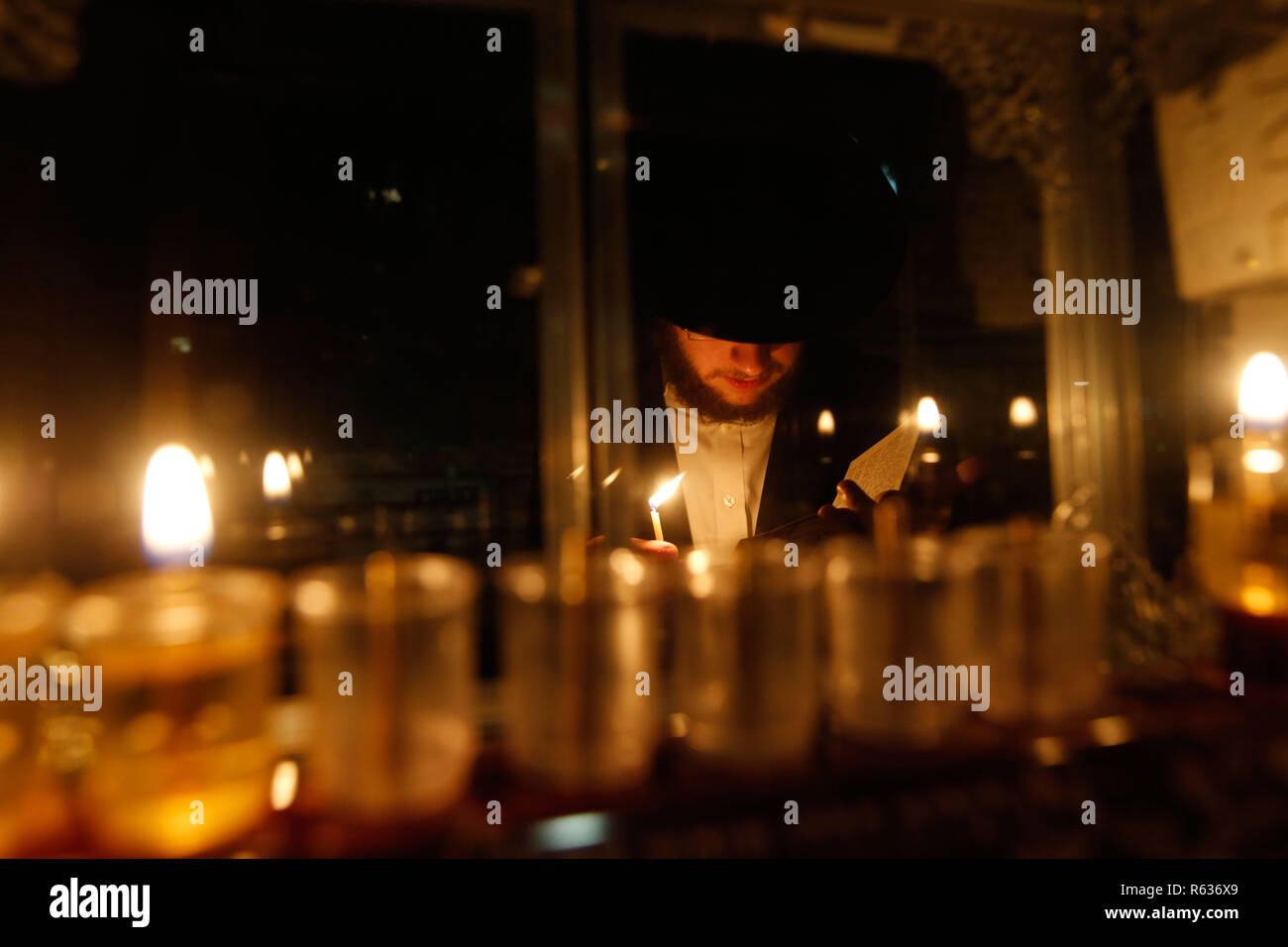 Jerusalem. 3rd Dec, 2018. An ultra-Orthodox Jewish man lights a candle during Hanukkah in Mea Shearim neighborhood in Jerusalem, on Dec. 3, 2018. Hanukkah, also known as the Festival of Lights and Feast of Dedication, is an eight-day Jewish holiday commemorating the rededication of the Holy Temple (the Second Temple) in Jerusalem at the time of the Maccabean Revolt against the Seleucid Empire of the 2nd Century B.C. Credit: Gil Cohen Magen/Xinhua/Alamy Live News Stock Photo