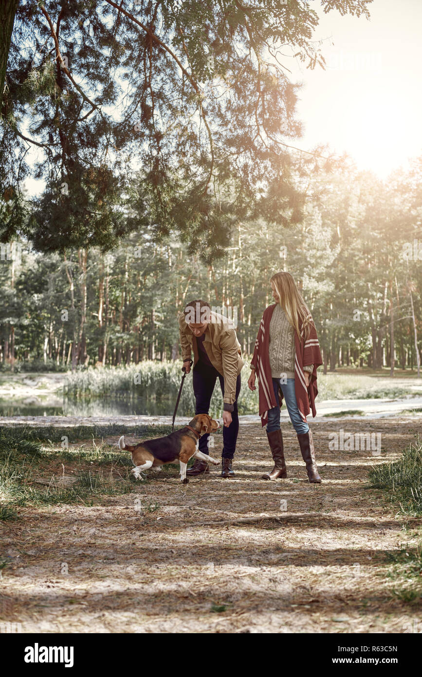 Young couple are walking with dog in forest Stock Photo - Alamy