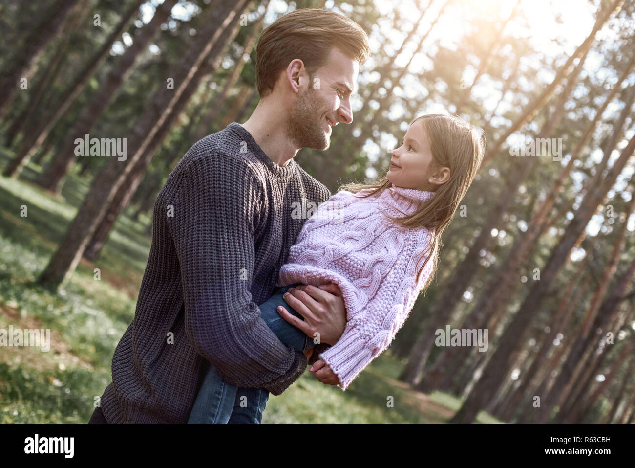 Young stylish father is holding his daughter in forest. Stock Photo