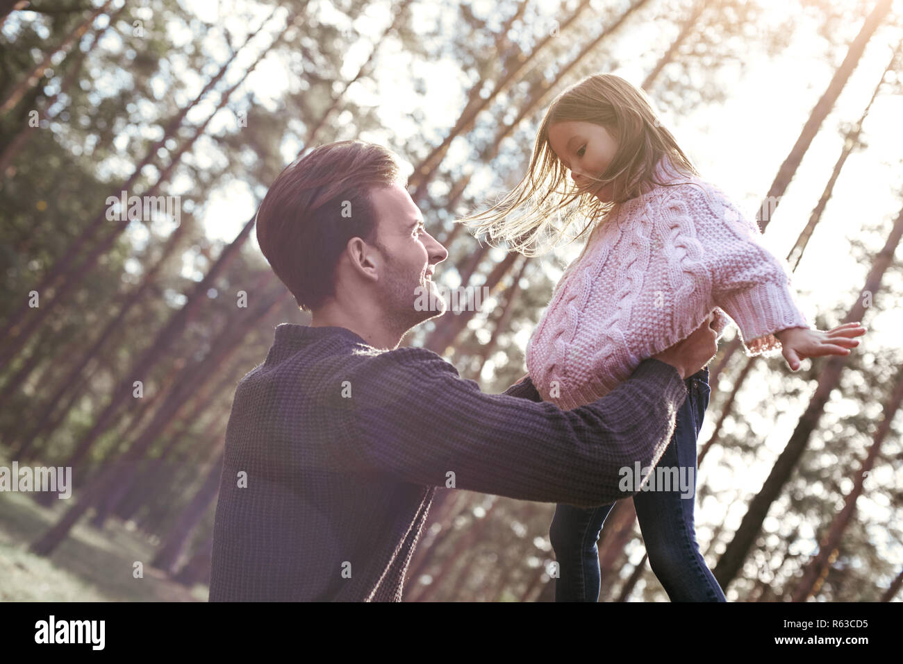 Young stylish father is holding his daughter in forest. Stock Photo