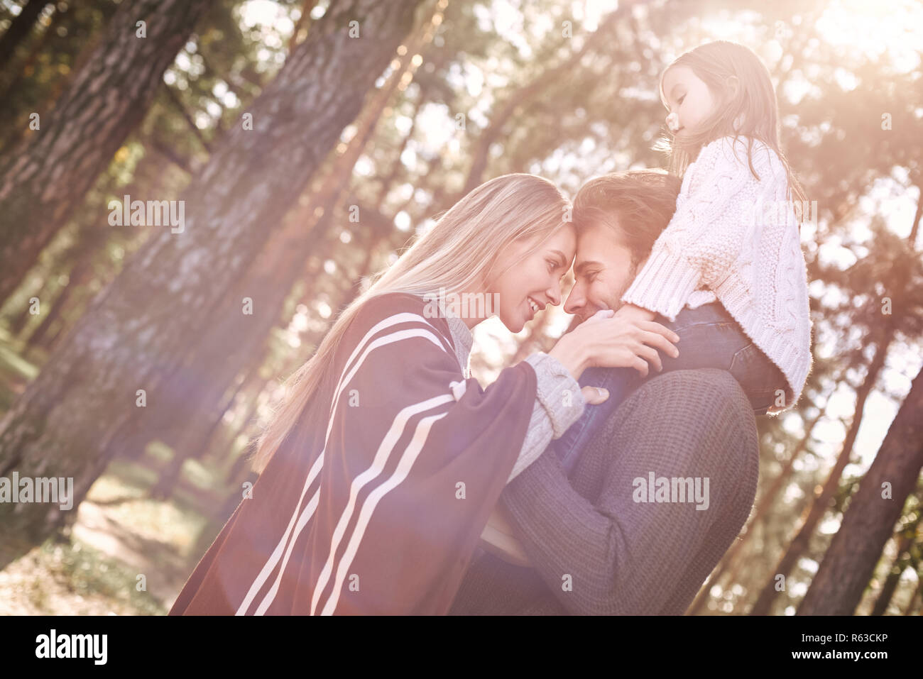 Young parents with little daughter in autumn forest. Close-up family portrait Stock Photo