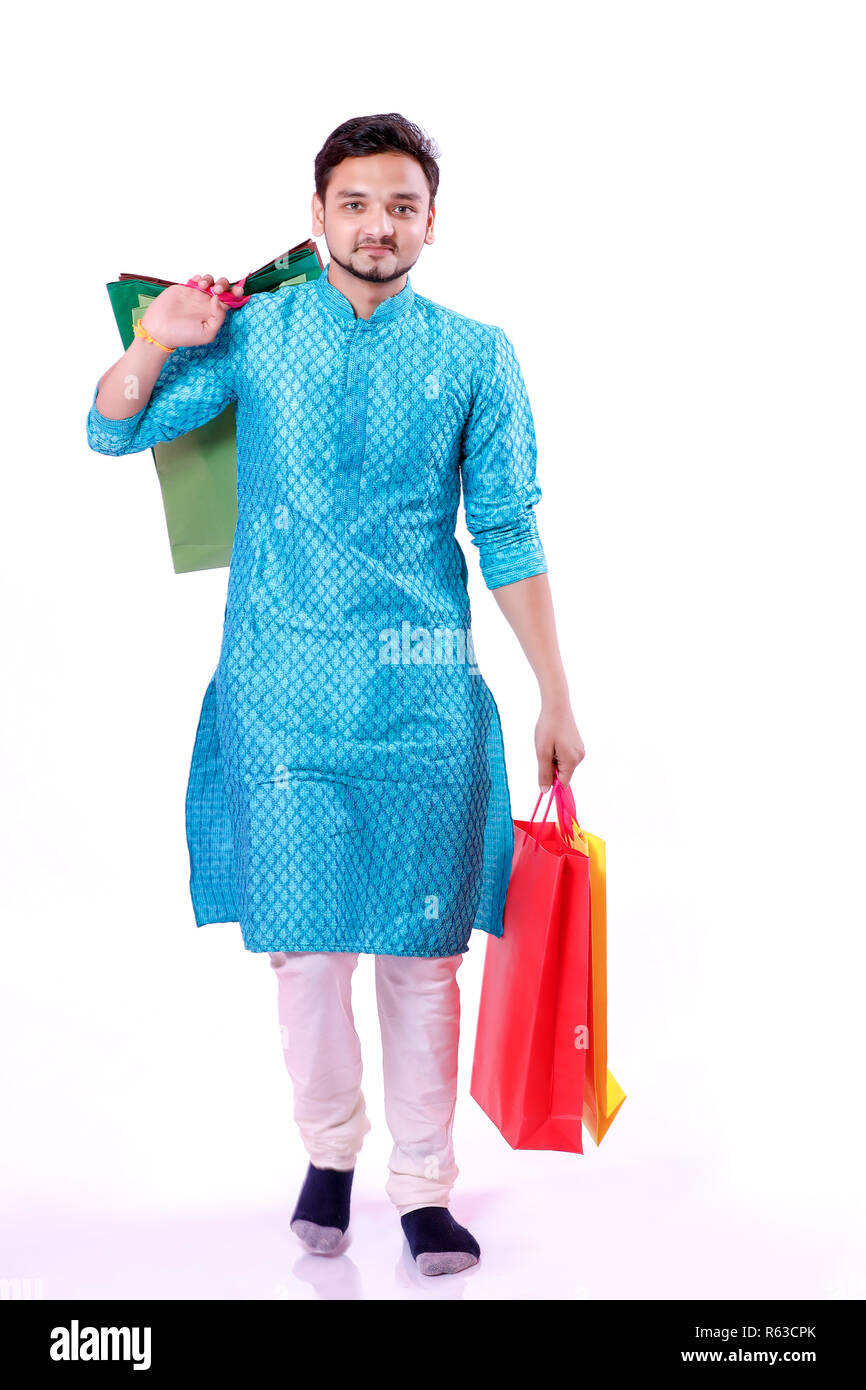 Indian man in ethnic wear with shopping bags, isolated over white background Stock Photo