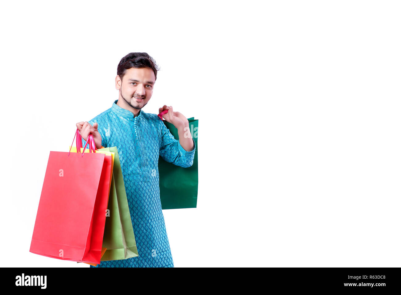 Indian man in ethnic wear with shopping bags, isolated over white background Stock Photo