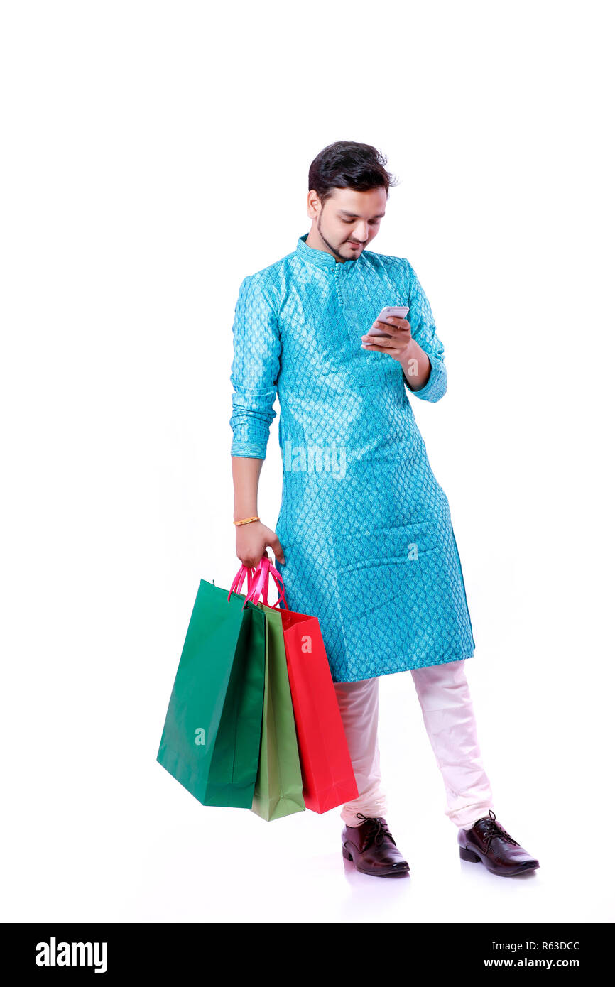 Indian man in ethnic wear with shopping bags and showing mobile screen , isolated over white background Stock Photo