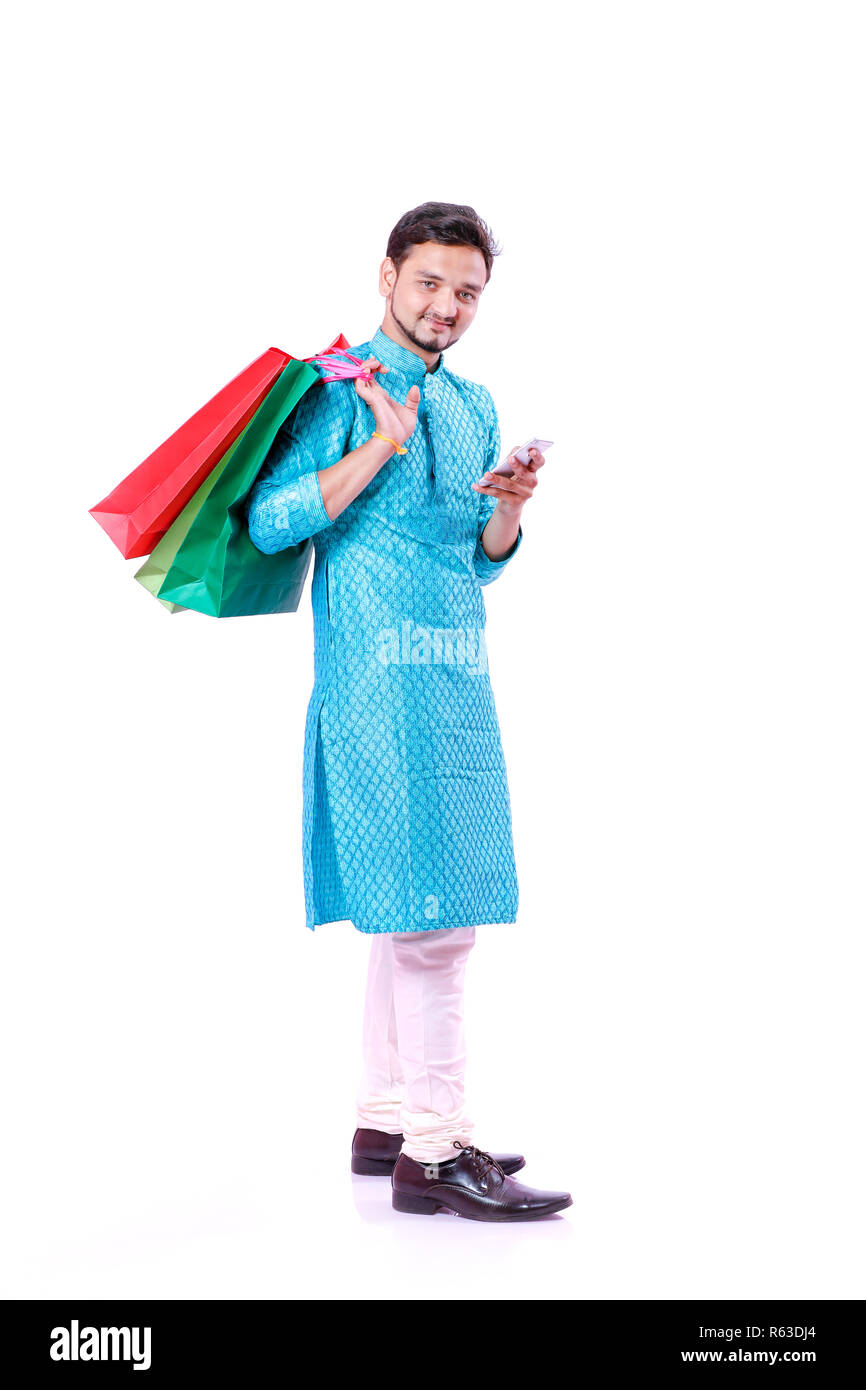 Indian man in ethnic wear with shopping bags and showing mobile screen , isolated over white background Stock Photo