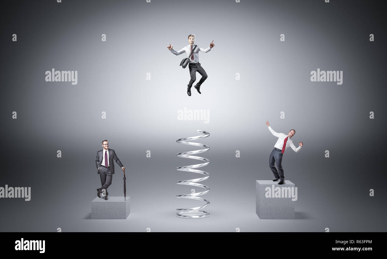 conceptual business image, businesspeople on block and on jumping with huge spring Stock Photo