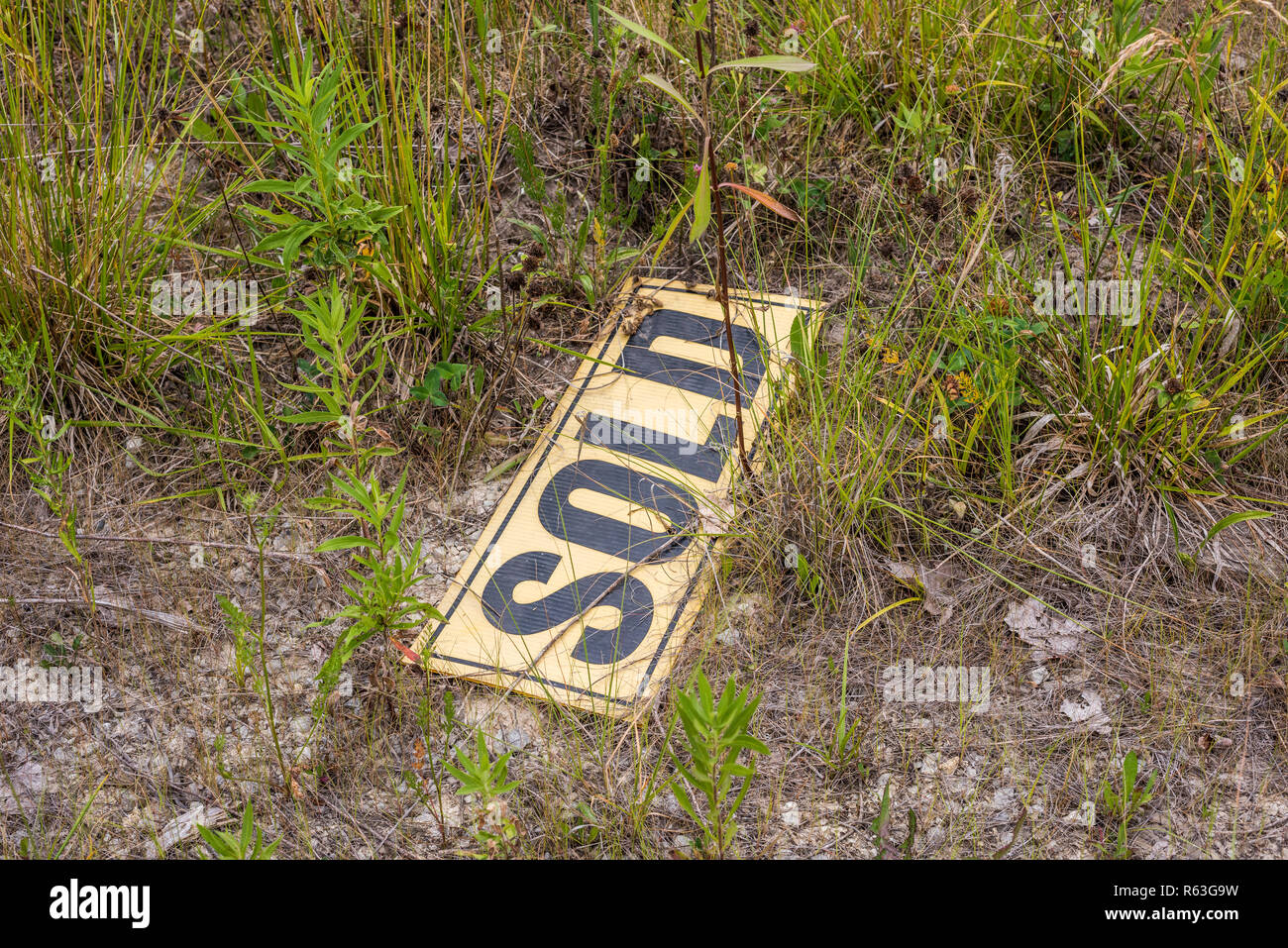 Real estate sold sign sitting in the weeds due to the Stock Market crash of 2008. Stock Photo