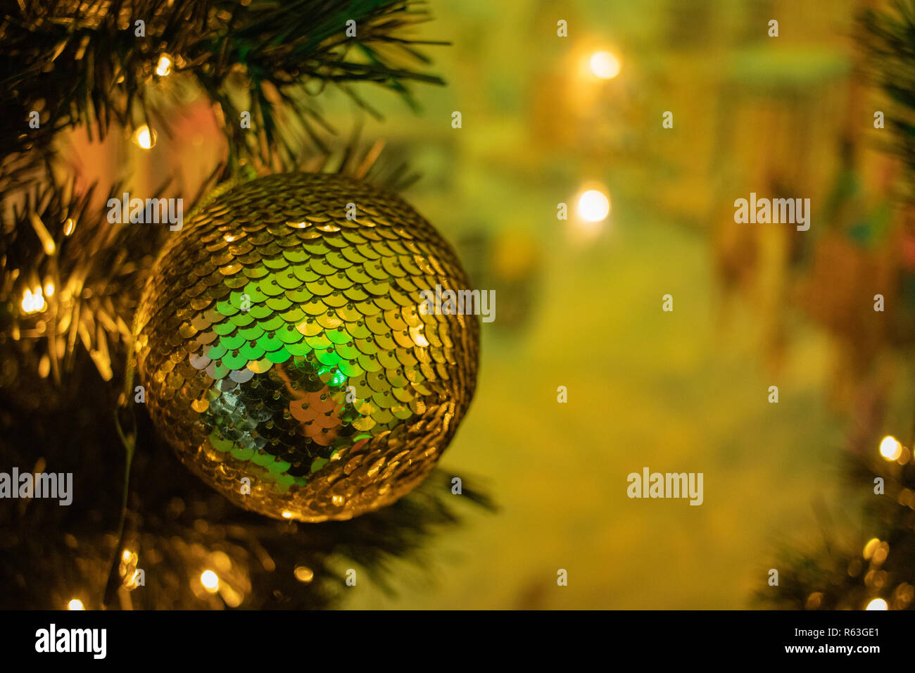 Golden bauble on a Christmas tree with Christmas lights in the background Stock Photo