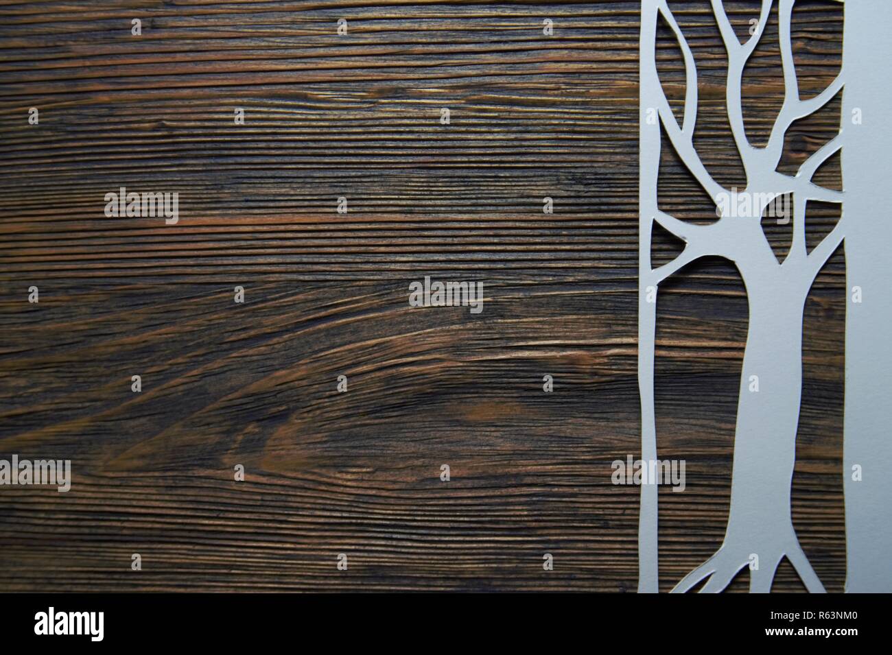 Tree shape cutout of white paper on dark wooden table surface with copy ...
