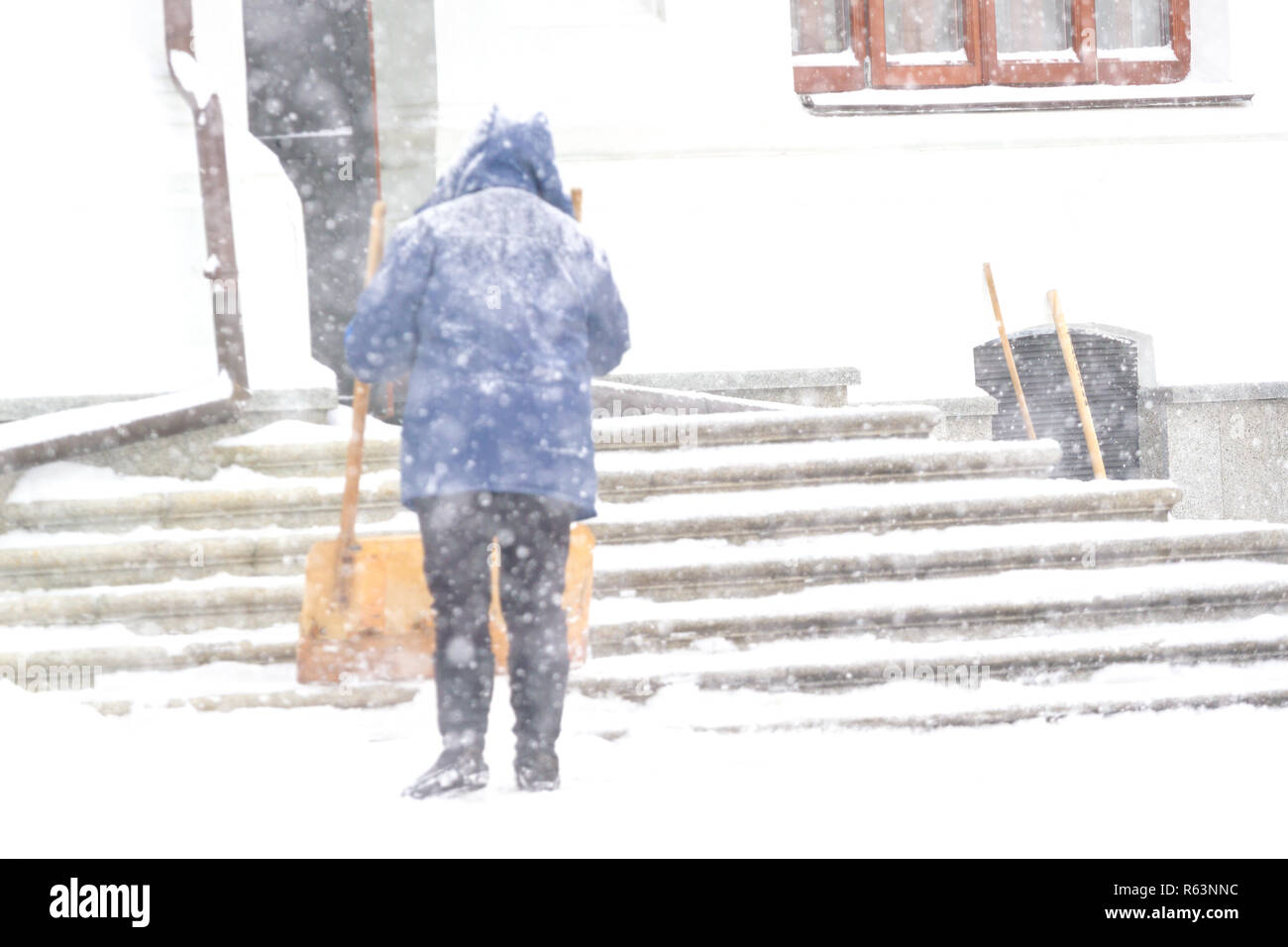 One women shovelling snow in the snowstrom. Cleaning stairs Stock Photo ...