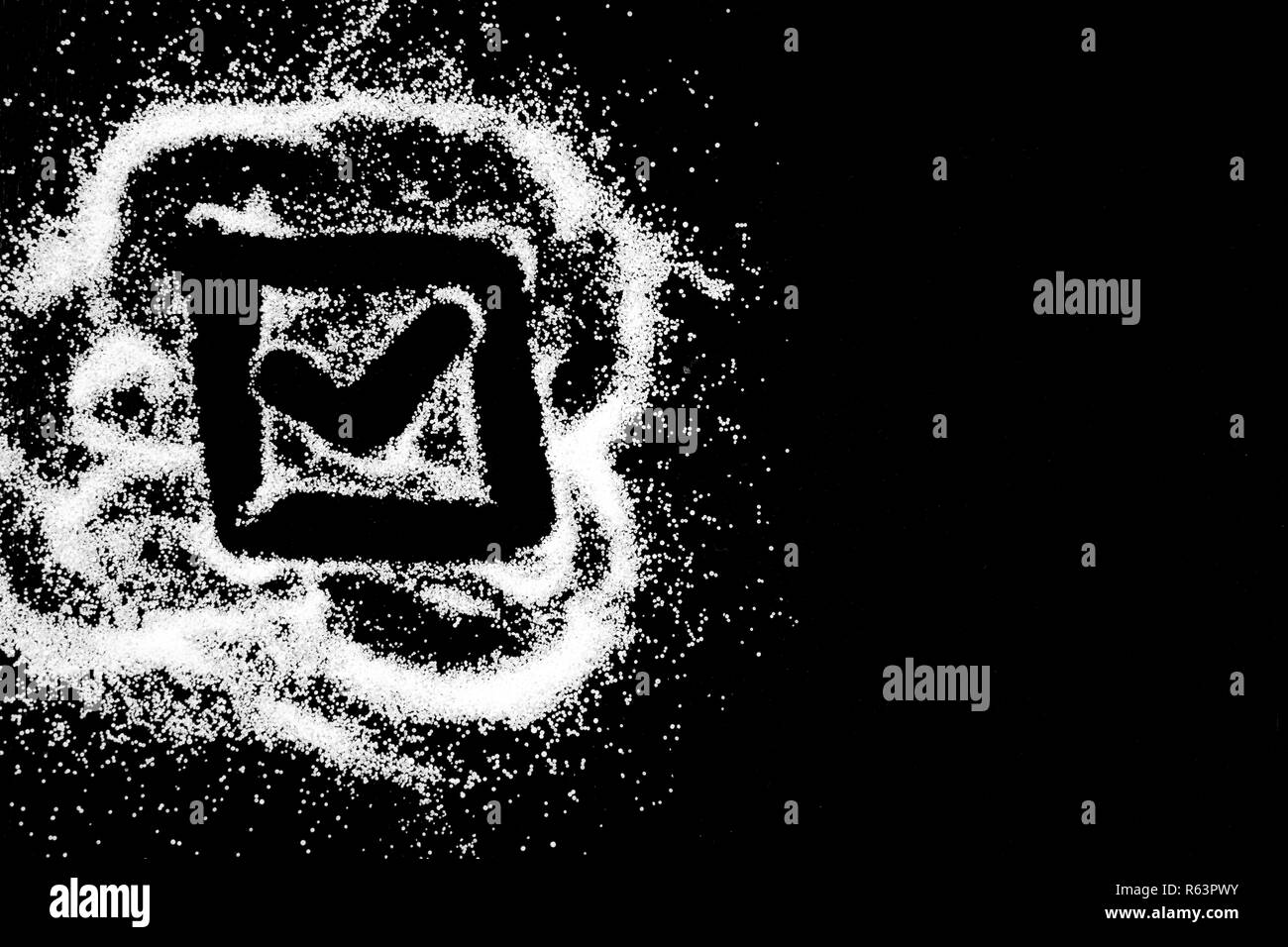 Checking mark symbol in checkbox drawing by finger on white snow salt powder spot cloud in left side on black background. Tick concept with place for text. Copy space. Stock Photo