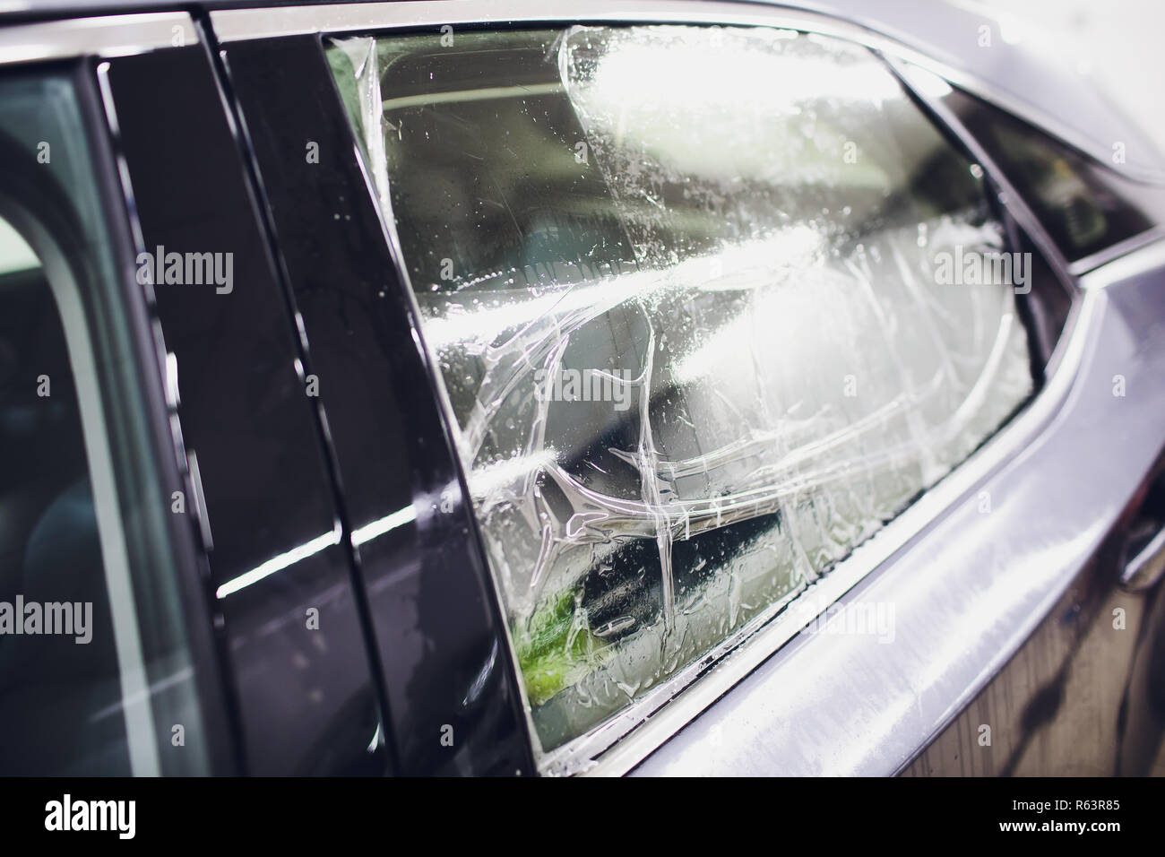 Applying Tinting Foil On Car Window In Garage Stock Photo