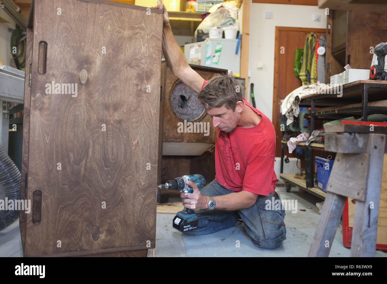 A carpenter finishing a large speaker cabinet. Stock Photo