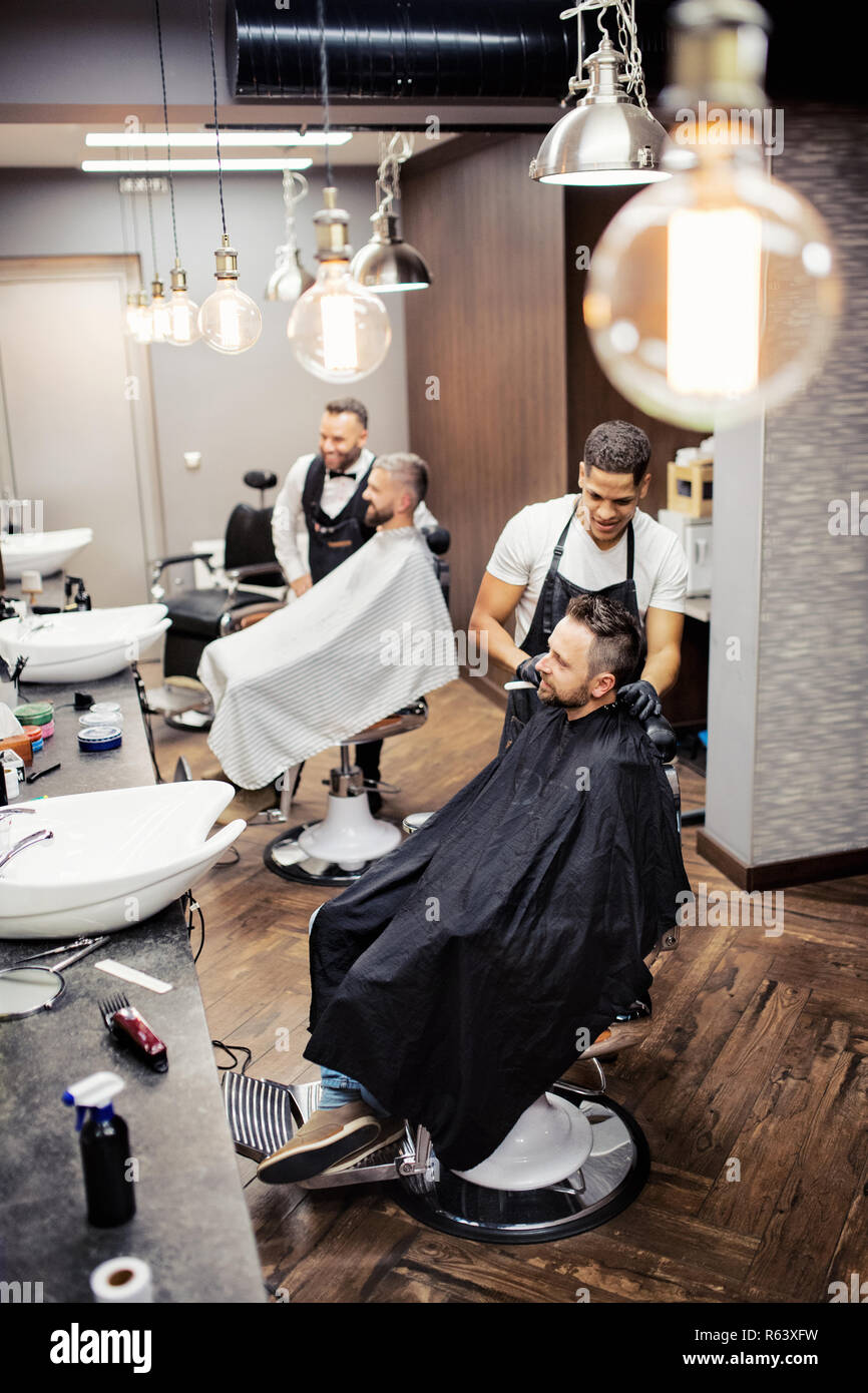 High angle view of man clients visiting haidresser and hairstylist in barber shop. Stock Photo