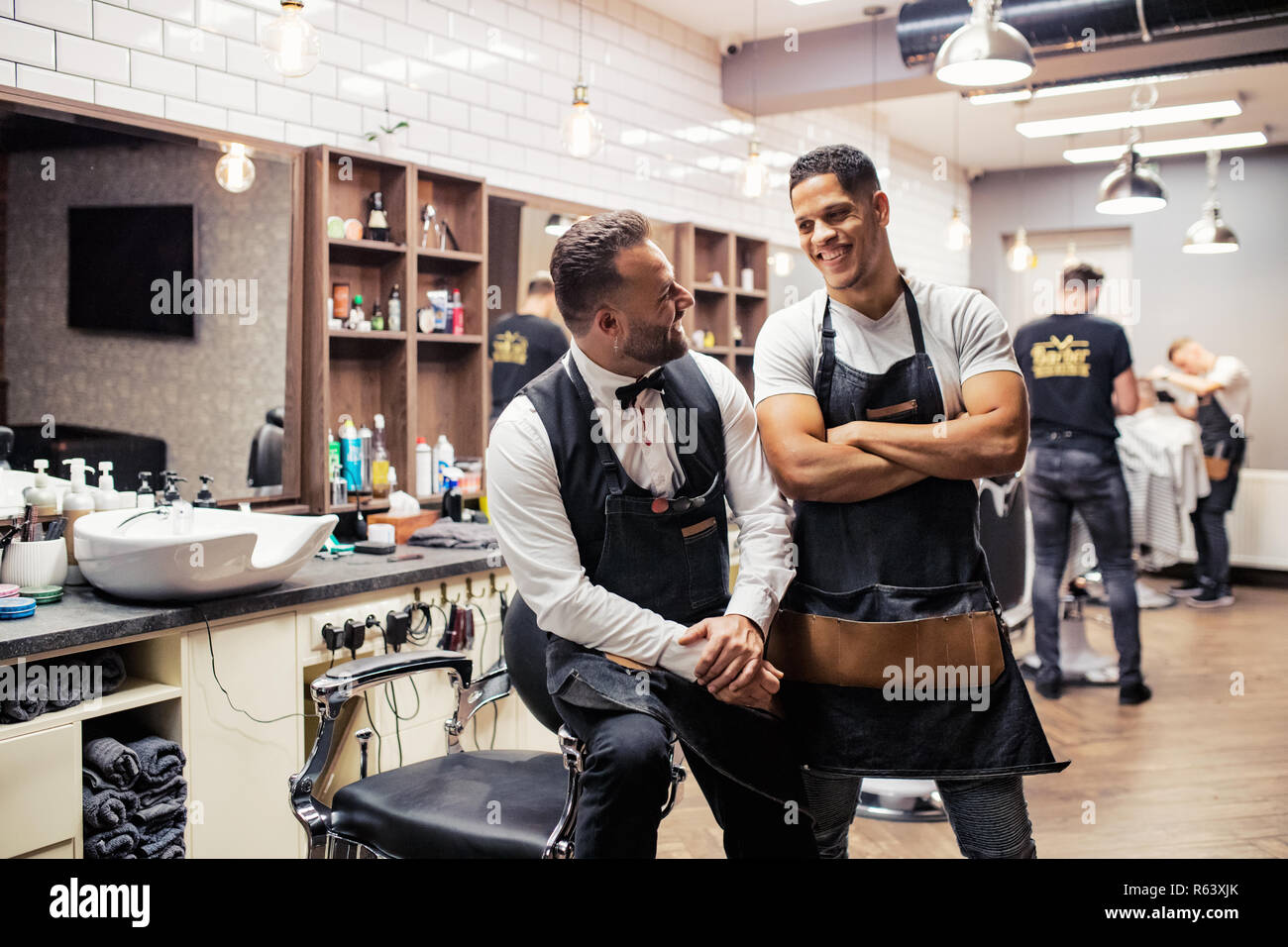 Two male haidressers and hairstylists sitting in barber shop. Stock Photo