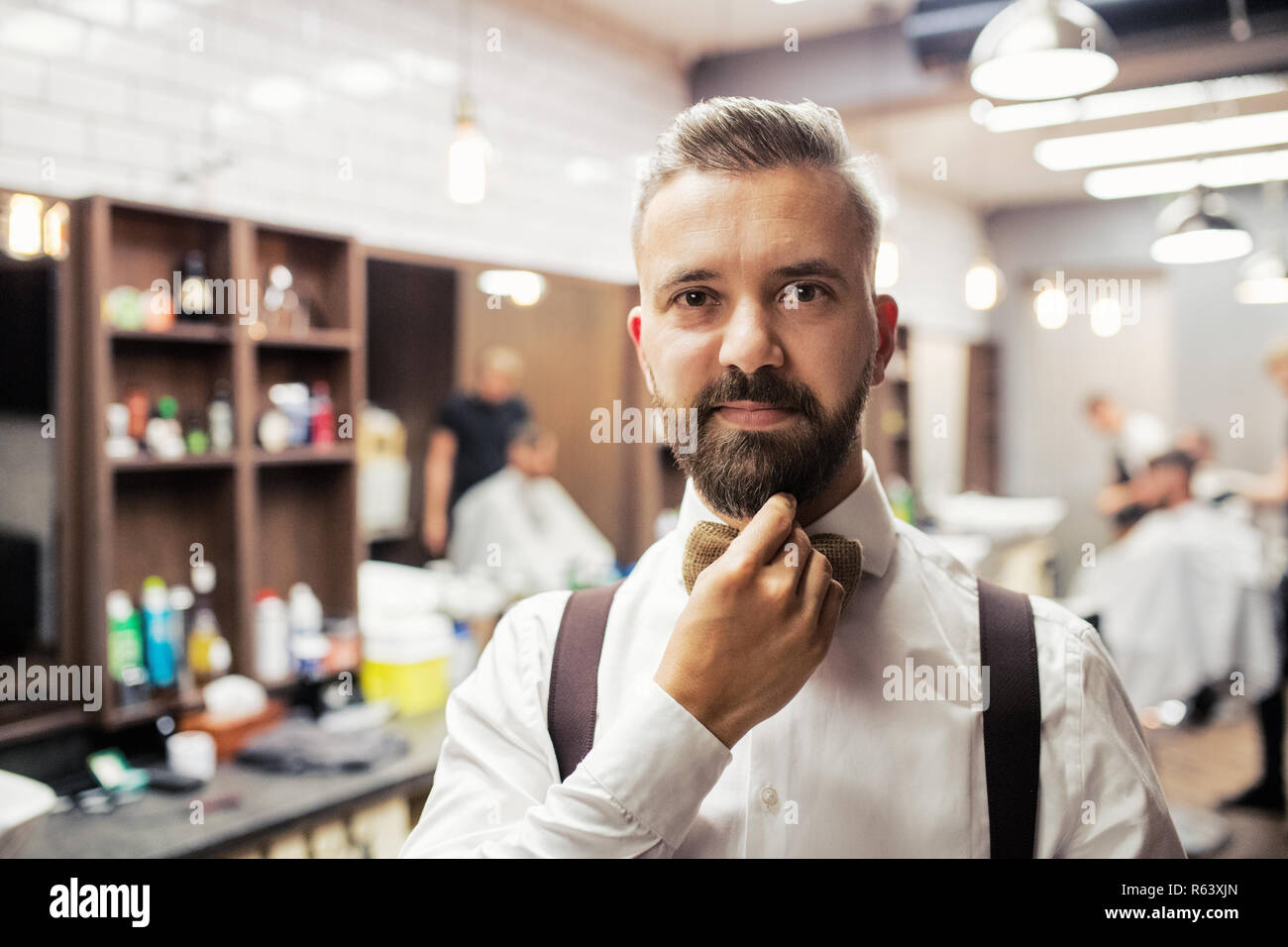 A portrait of handsome hipster man client standing in barber shop. Stock Photo
