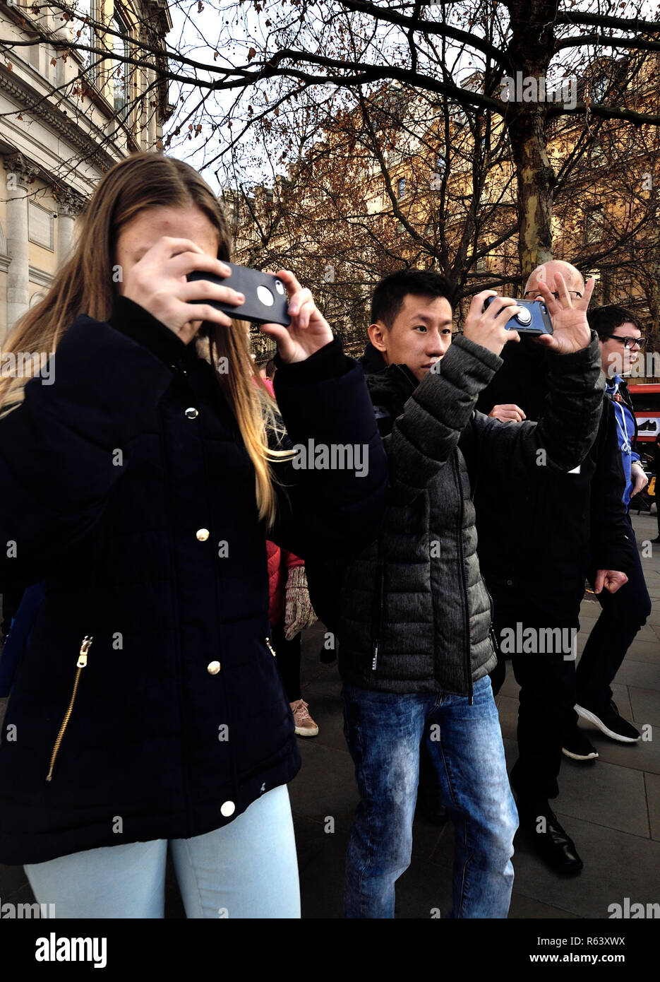 Young tourists filming on their mobile phone whie walking, Trafalgar Square, London, England, UK. Stock Photo
