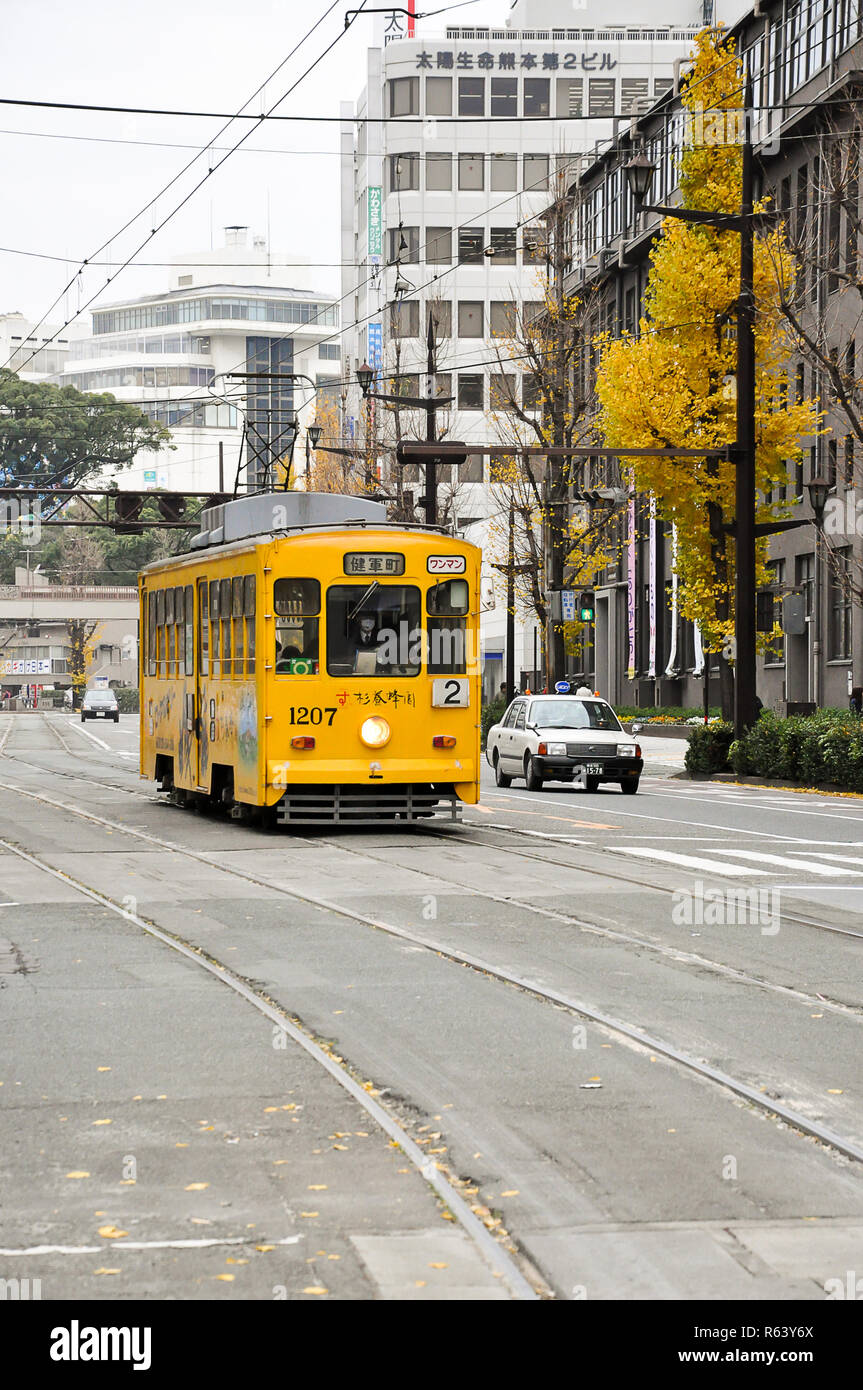 Kumamoto, Japan -December 15, 2009: Classic yellow tram of Kumamoto city with yellow ginko leaves background Stock Photo