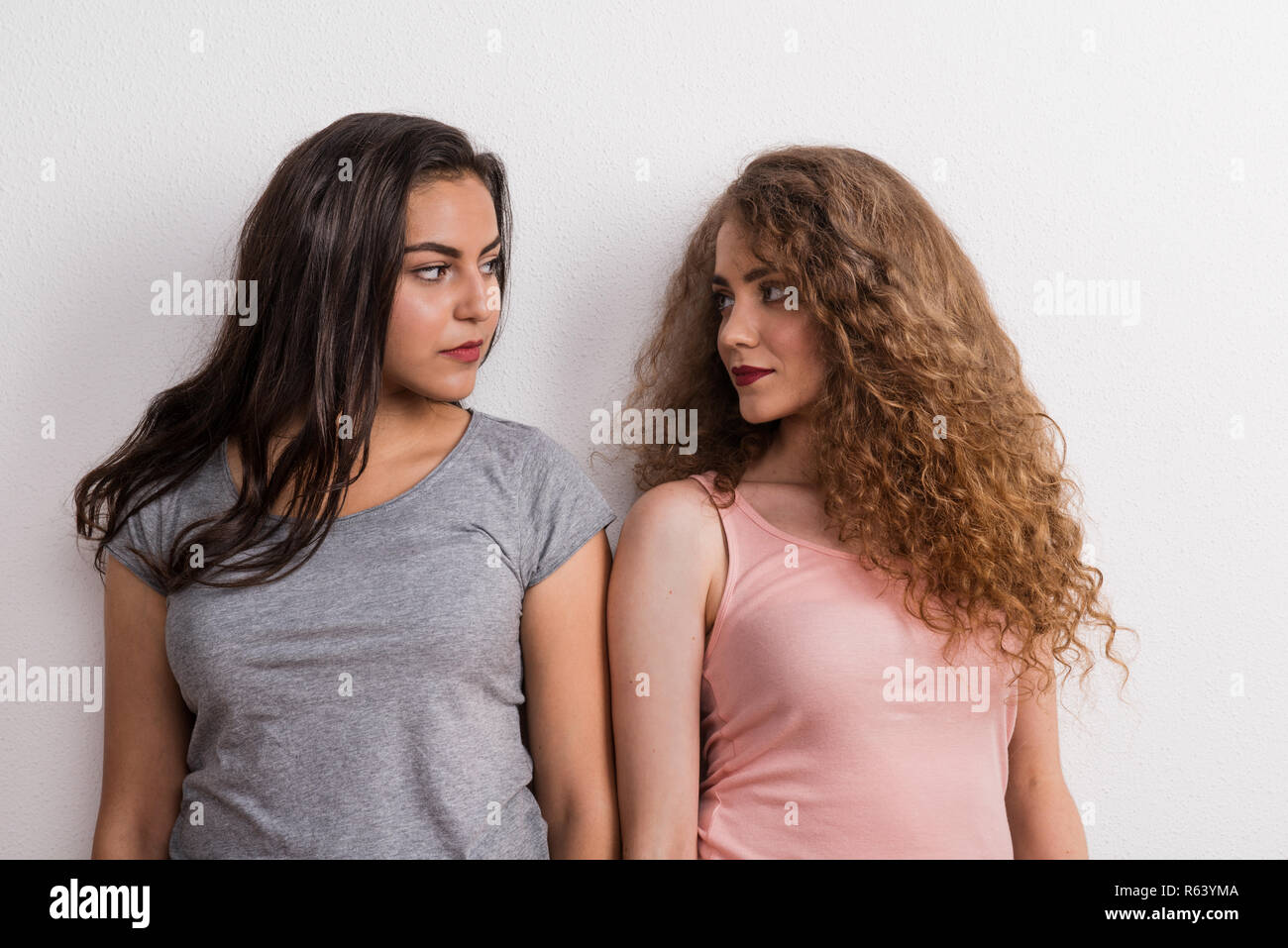 Young beautiful serious women in studio, looking at each other. Stock Photo