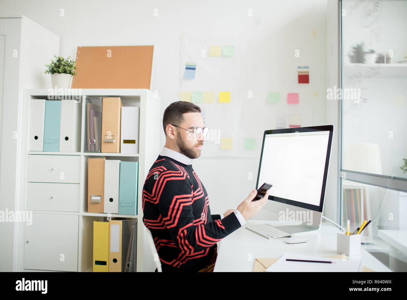 Serious man checking message on phone in office Stock Photo