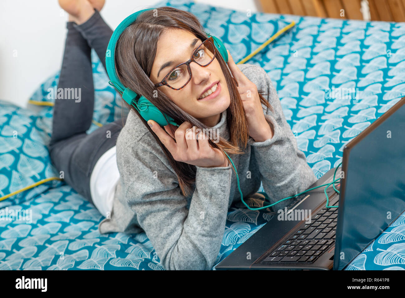 a young brunette woman lying on the bed listening to music Stock Photo ...