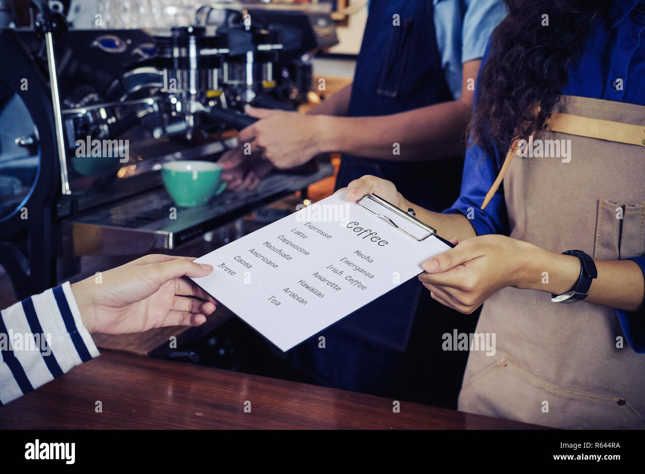 Baristas are recommending coffee menu to customer. Cafe restaurant service, food and drink industry concept. Stock Photo