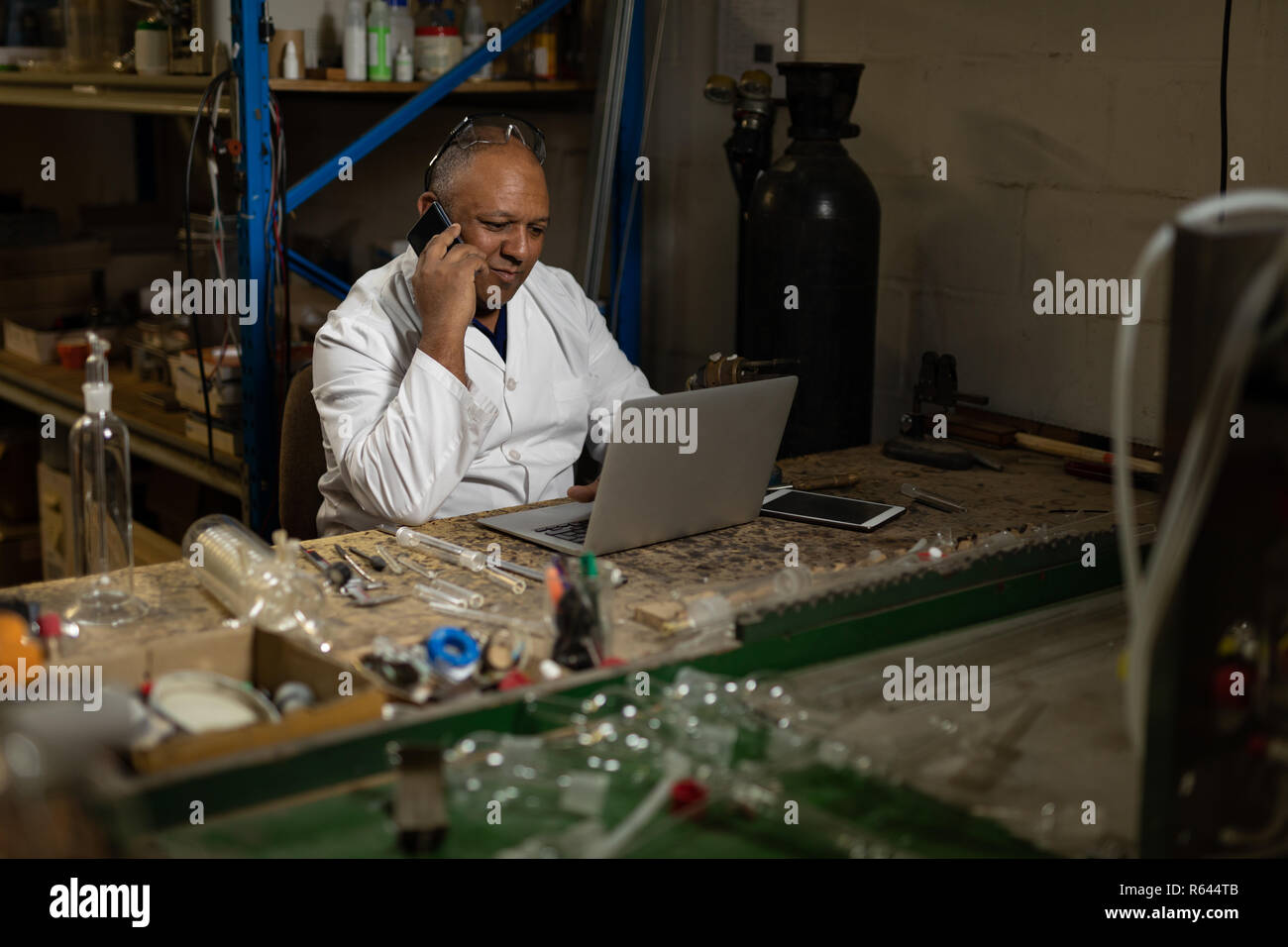 Worker talking on mobile phone while using laptop Stock Photo