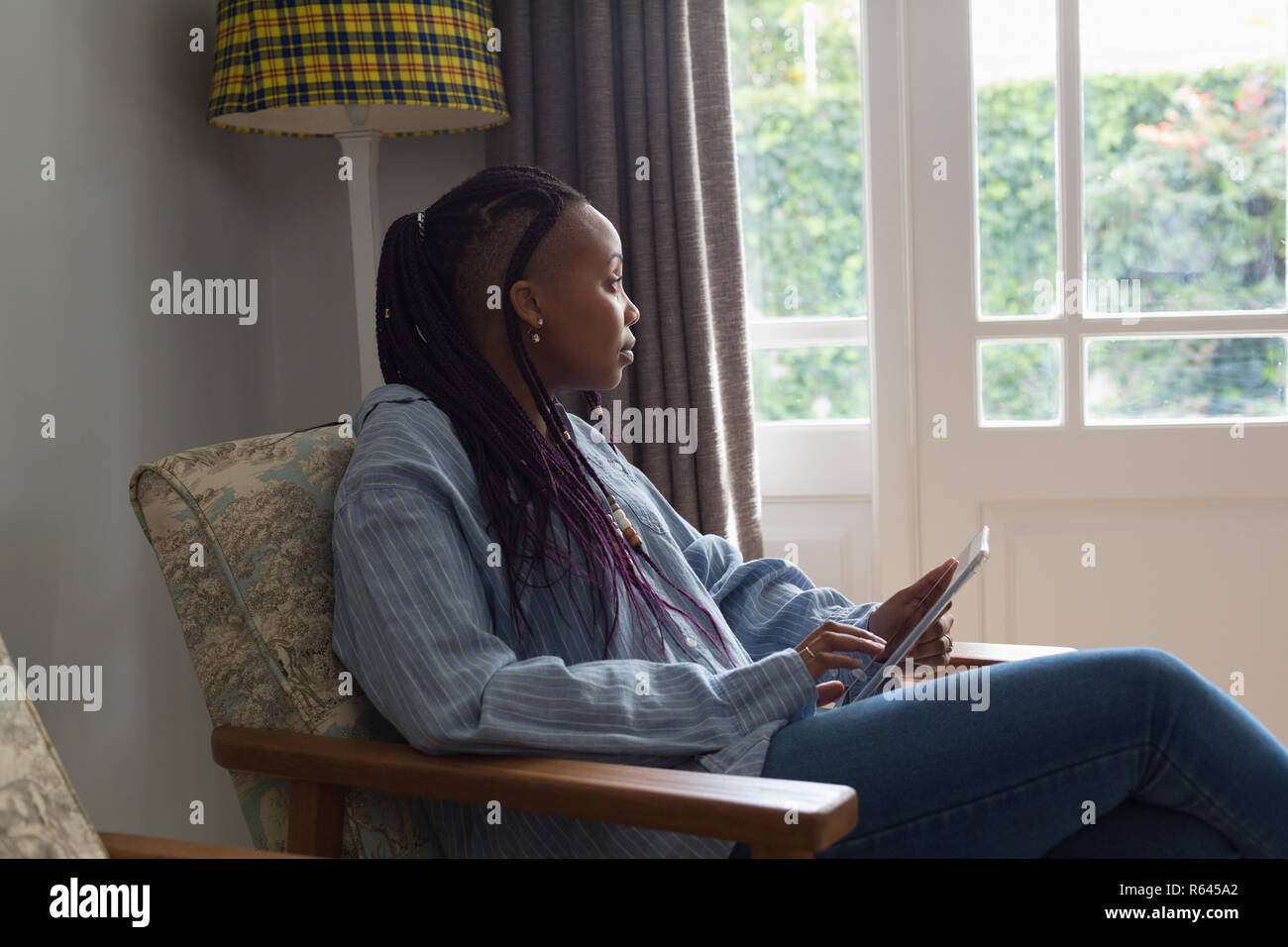 Thoughtful woman using digital tablet in a liviing room Stock Photo