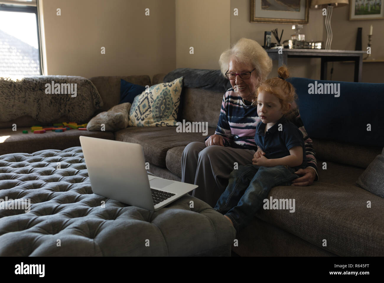 Grandmother and granddaughter making video call on laptop in living room Stock Photo