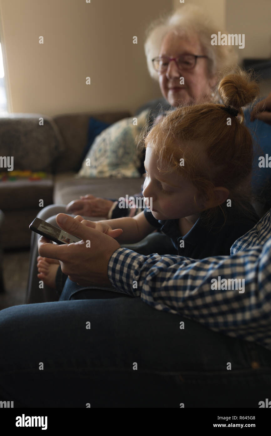 Multi generation family using mobile phone on sofa in living room Stock Photo