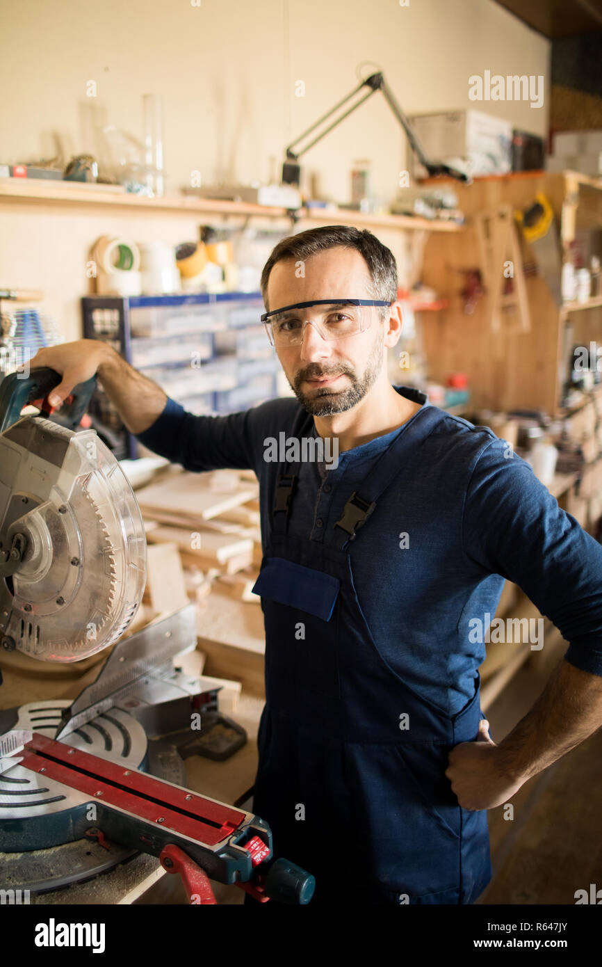 Mature Carpenter Posing in Sunlit Workshop Stock Photo