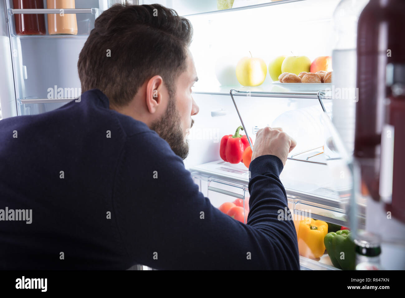 Man Removing Water Bottle From Refrigerator Stock Photo