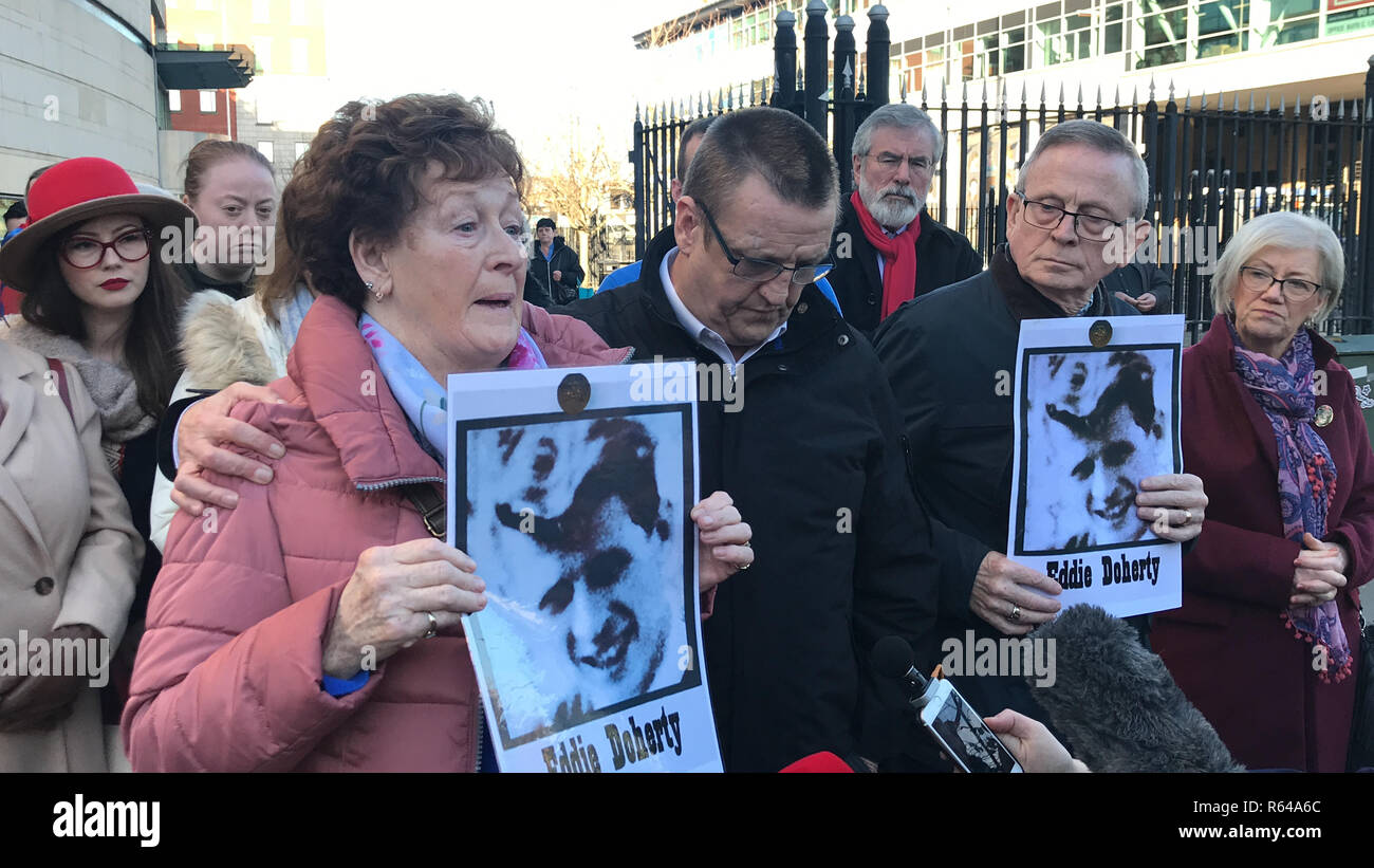 The family, (left to right) Kathleen McCarry, Patrick Doherty and John Doherty, of Eddie Doherty, one of those killed in shootings in Ballymurphy in 1971, watched by former Sinn Fein President Gerry Adams, outside Belfast Coroner's Court ahead of inquest proceedings. Stock Photo