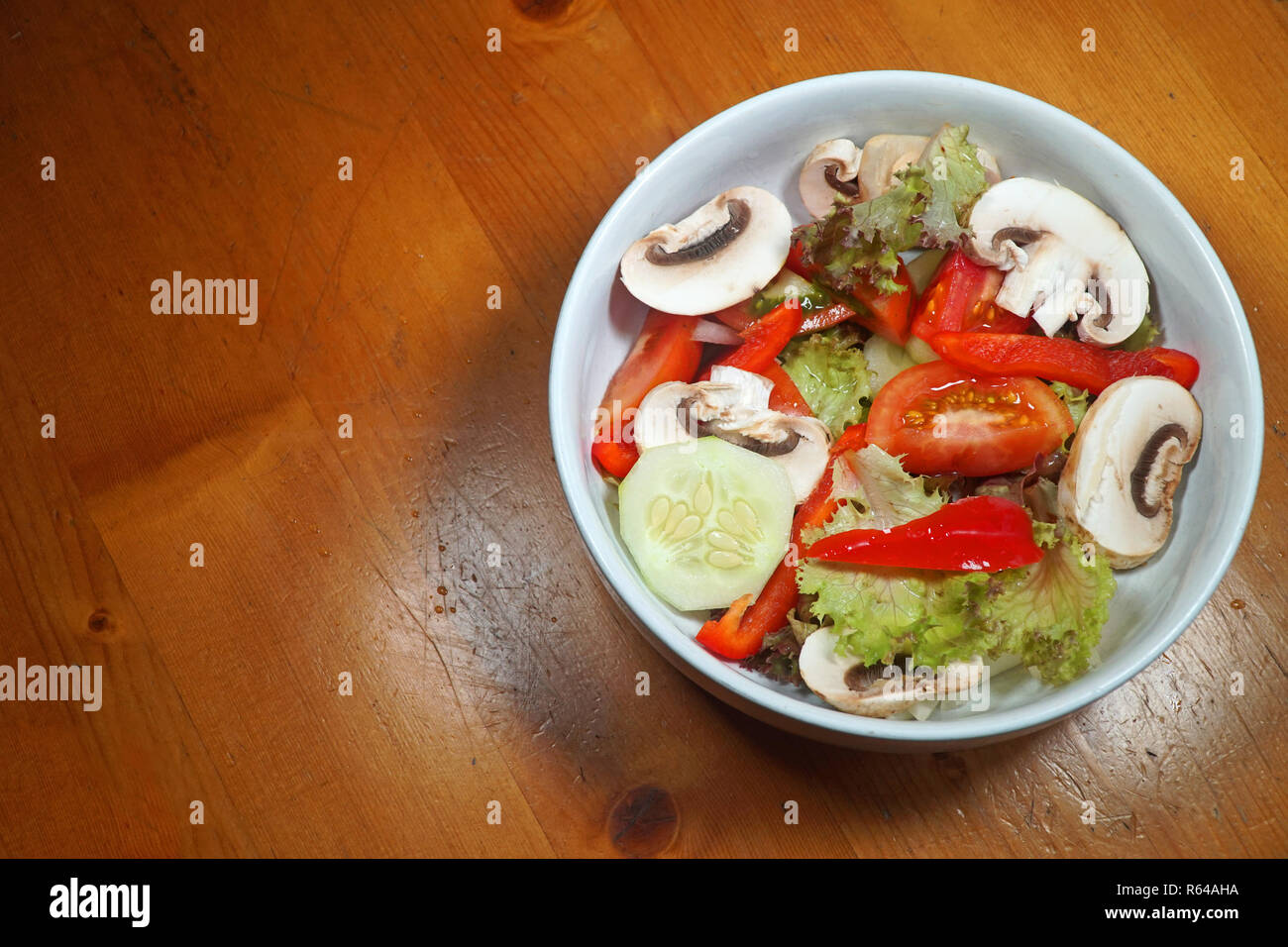 A bowl of fresh salad on a wooden table Stock Photo