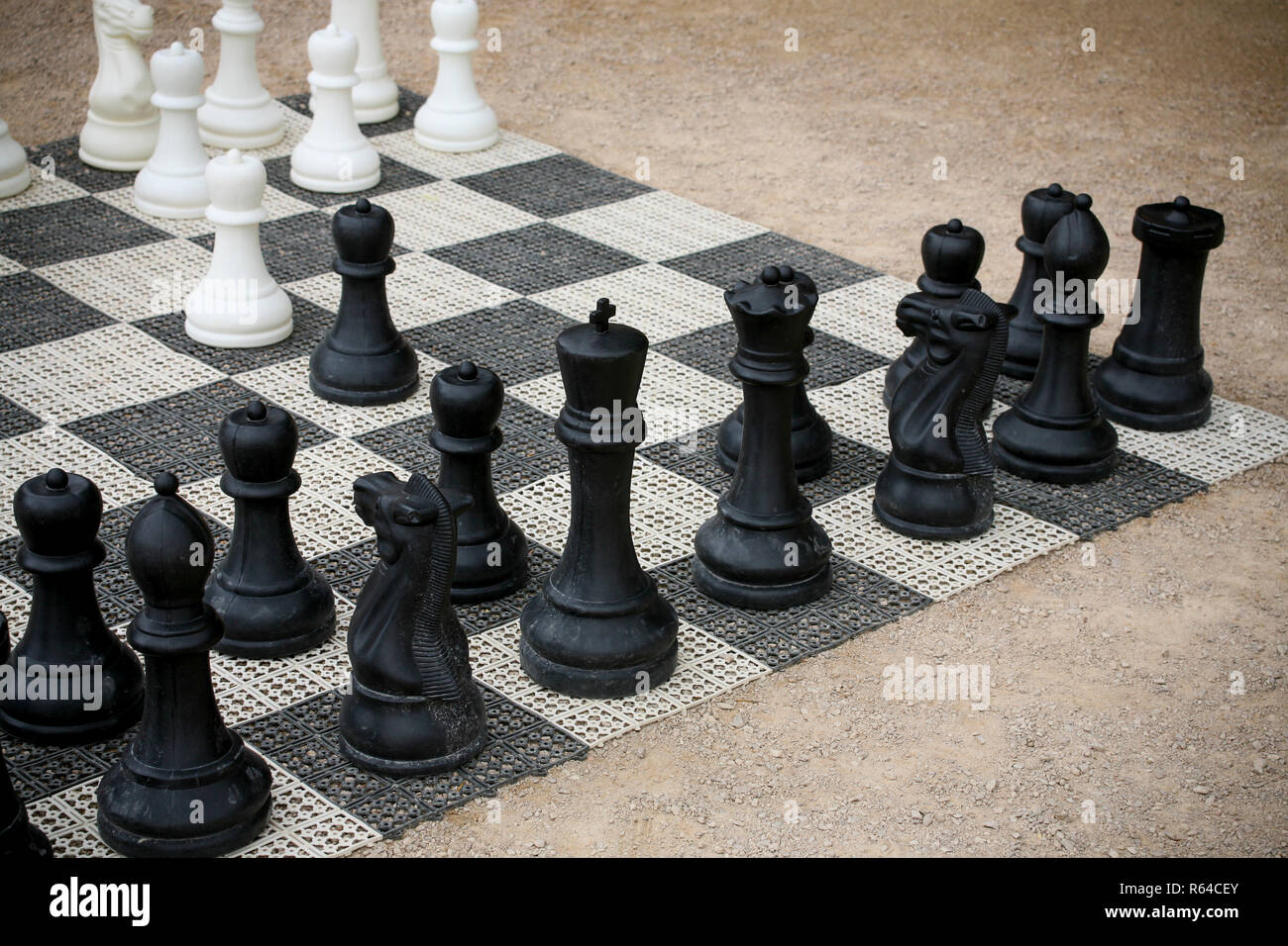 A completed chess game setup on a table with opposing chairs in a dark room  backlit by a bright window light - 3D render Stock Photo - Alamy