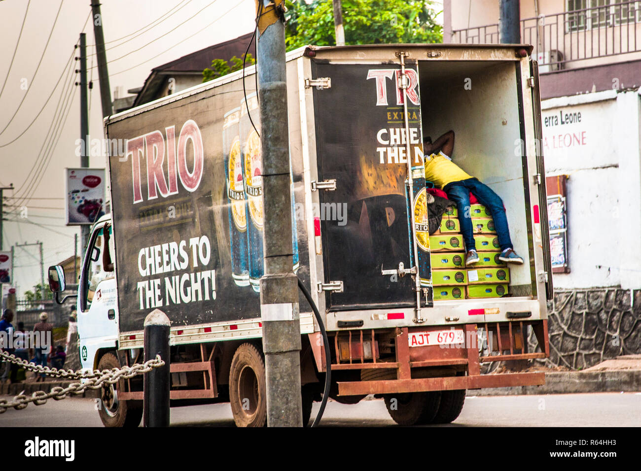 A man sleeps on the back of an open truck driving through Freetown (Sierra Leone) Stock Photo