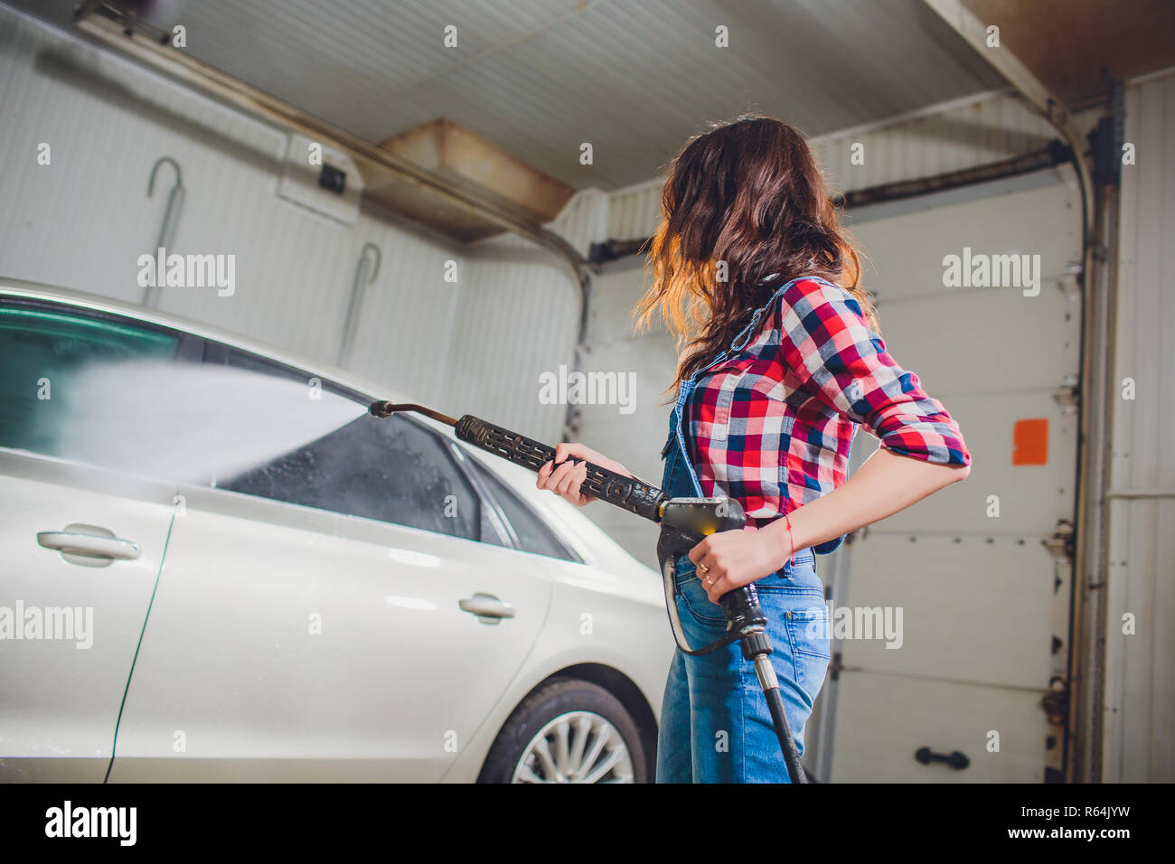 Attractive woman washing automobile manual car washing self service