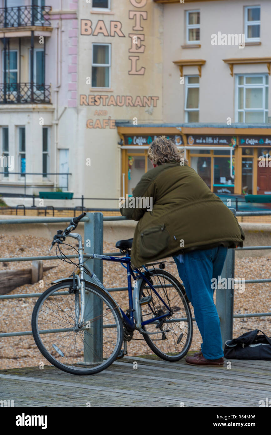 a man with a bicycle on Bognor regis pier looking at the run down and