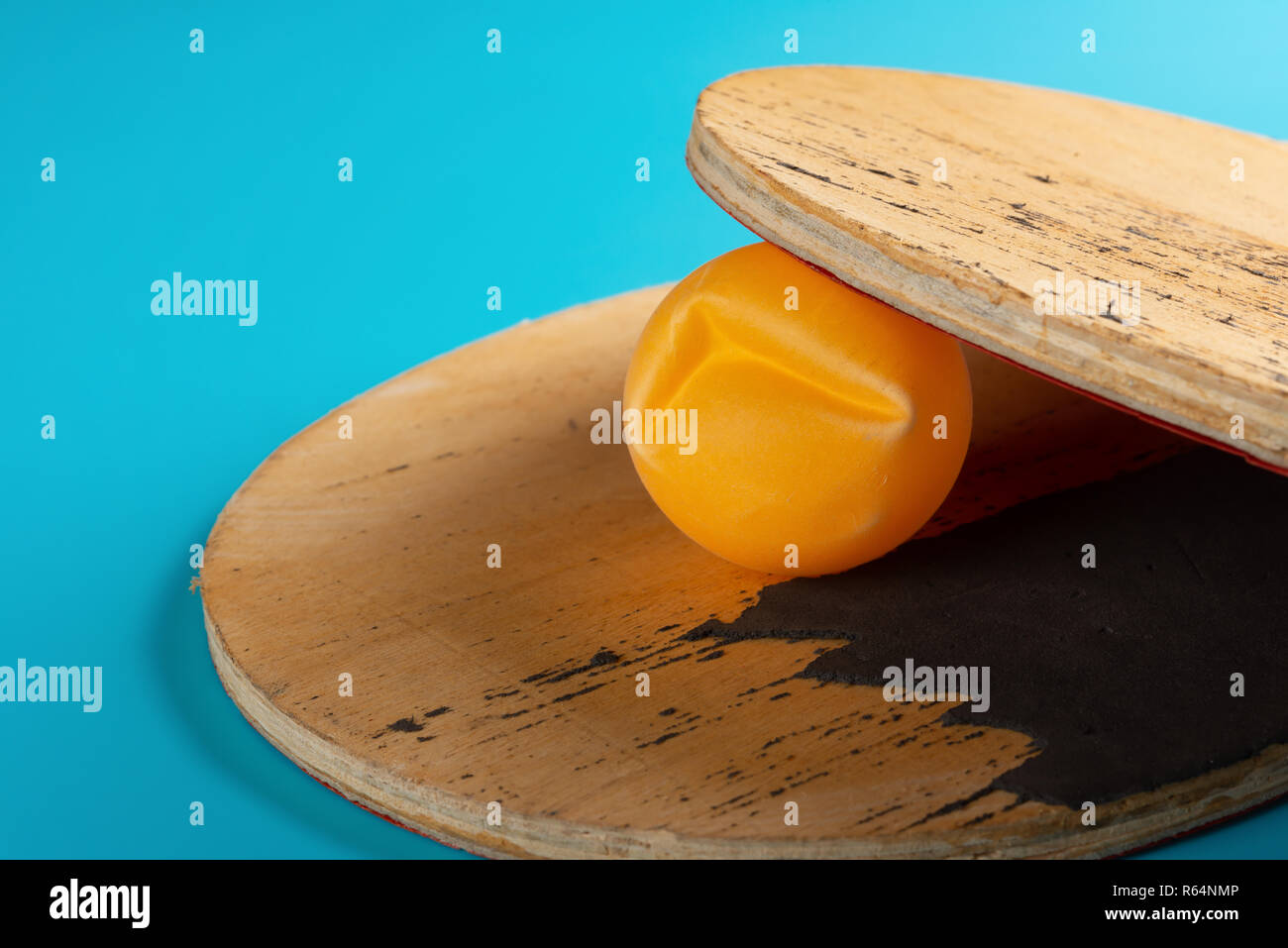 dent pingpong ball and pair of rackets on blue background Stock Photo
